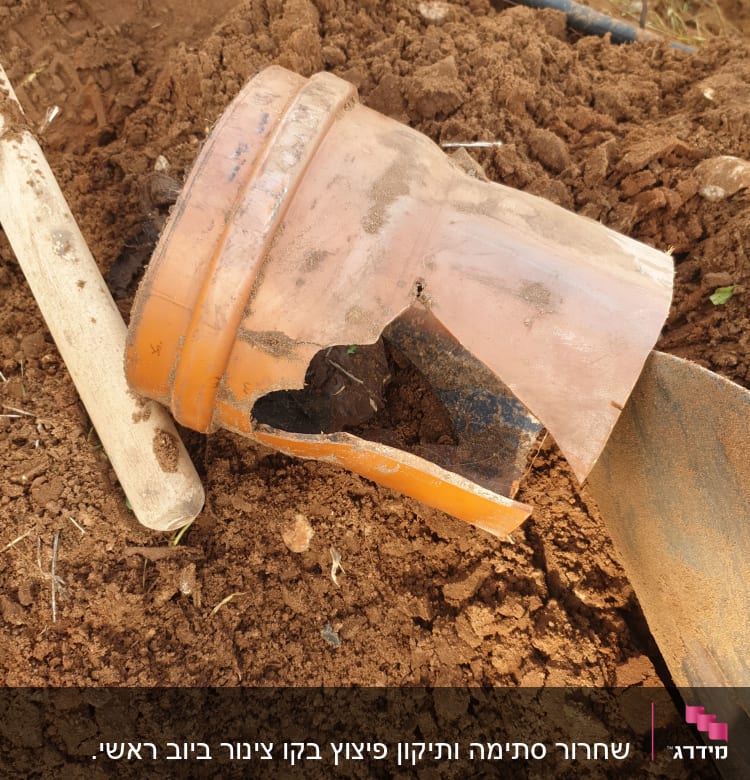 צינור כתום שבור באדמה עם כלי עבודה